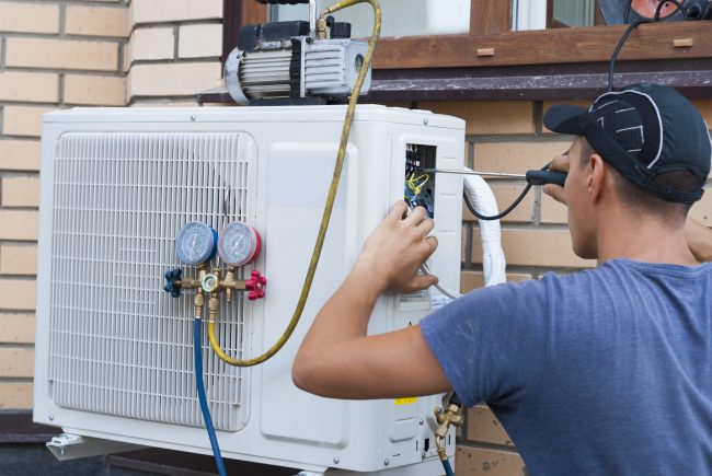 the worker installs the outdoor unit of the air conditioner on the wall of the house
